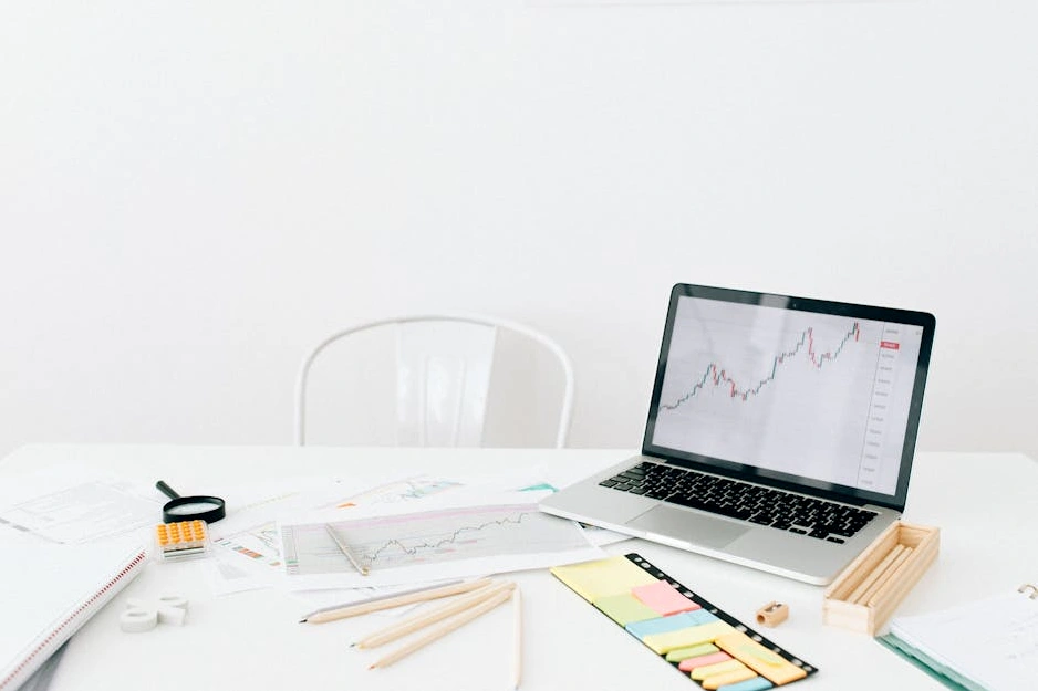 Ein Anleger analysiert Aktiendiagramme auf seinem Laptop und Smartphone.